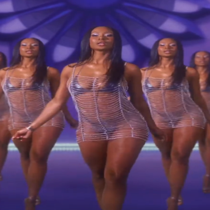 Person in a sheer, futuristic dress walks confidently in a mirrored setting, creating multiple reflections in a stylized pattern