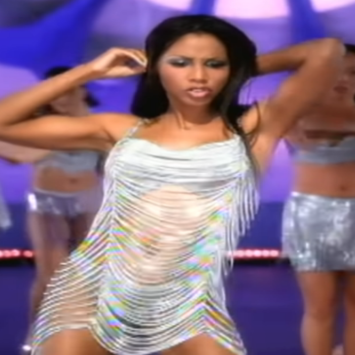 Singer in a shimmering fringe dress leads backup dancers in matching silver outfits, performing energetically