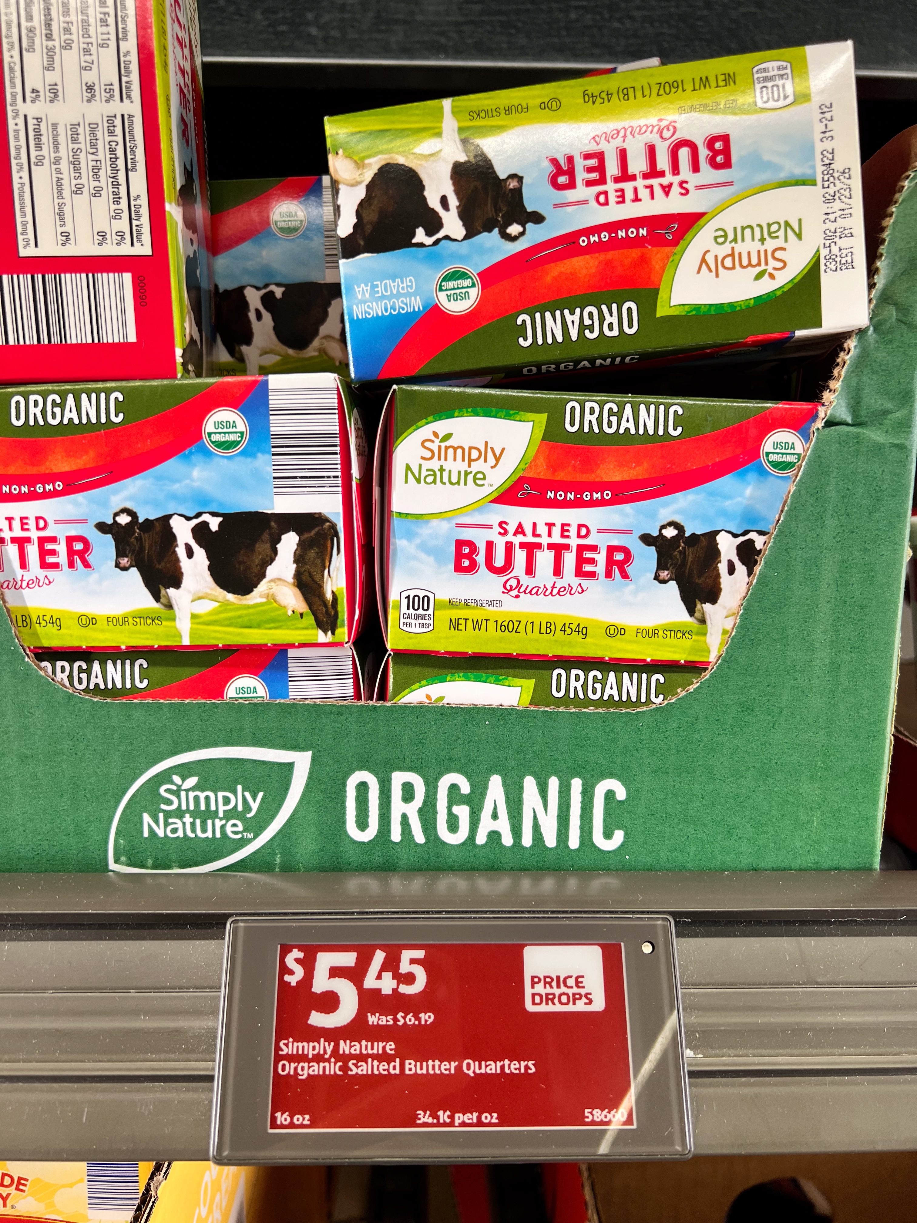 Boxes of Simply Nature Organic Salted Butter Quarters are stacked on a shelf, with a price tag showing $5.45, down from $6.19
