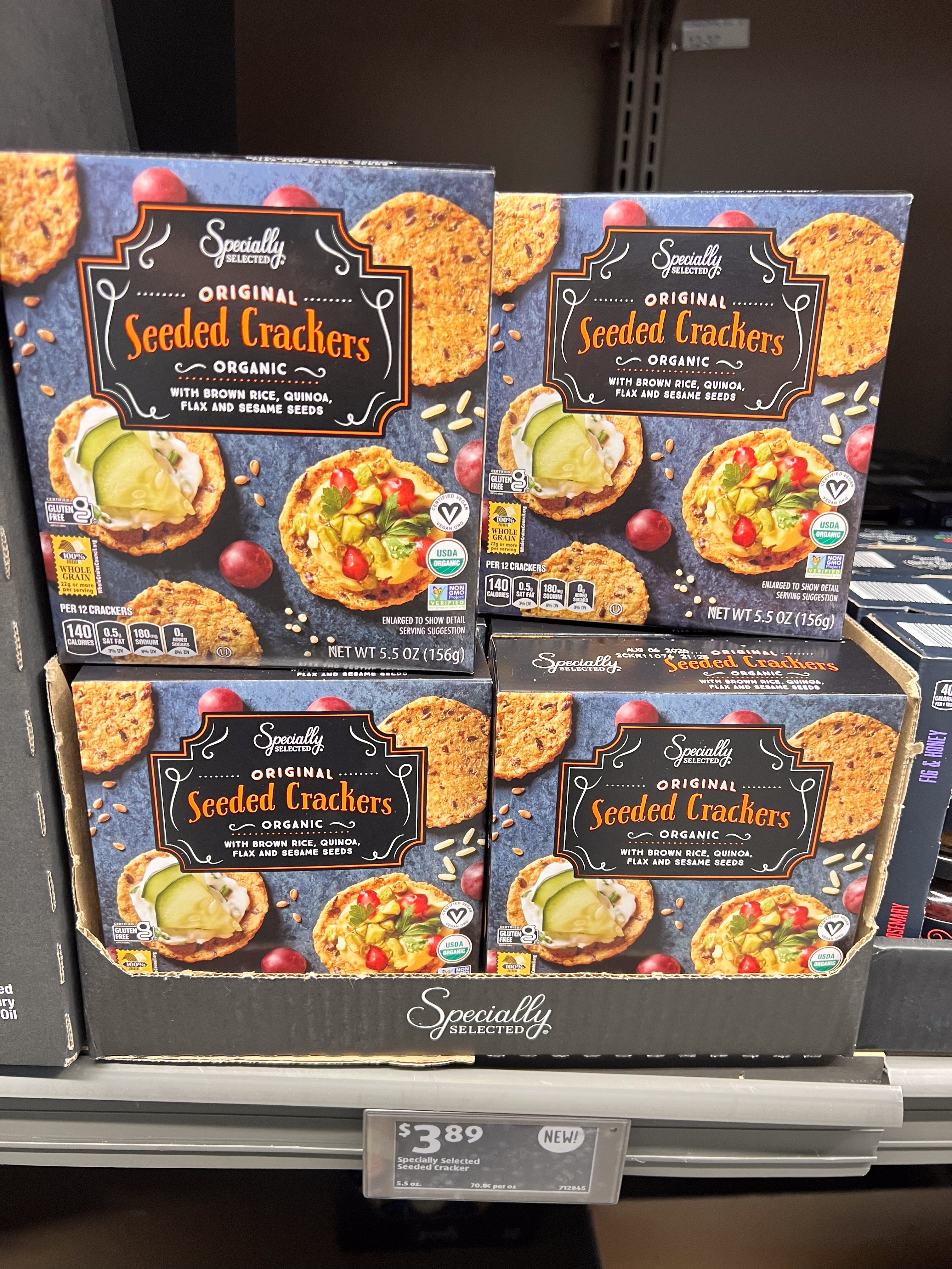 Boxes of organic seeded crackers on a store shelf, priced at $3.89 per box