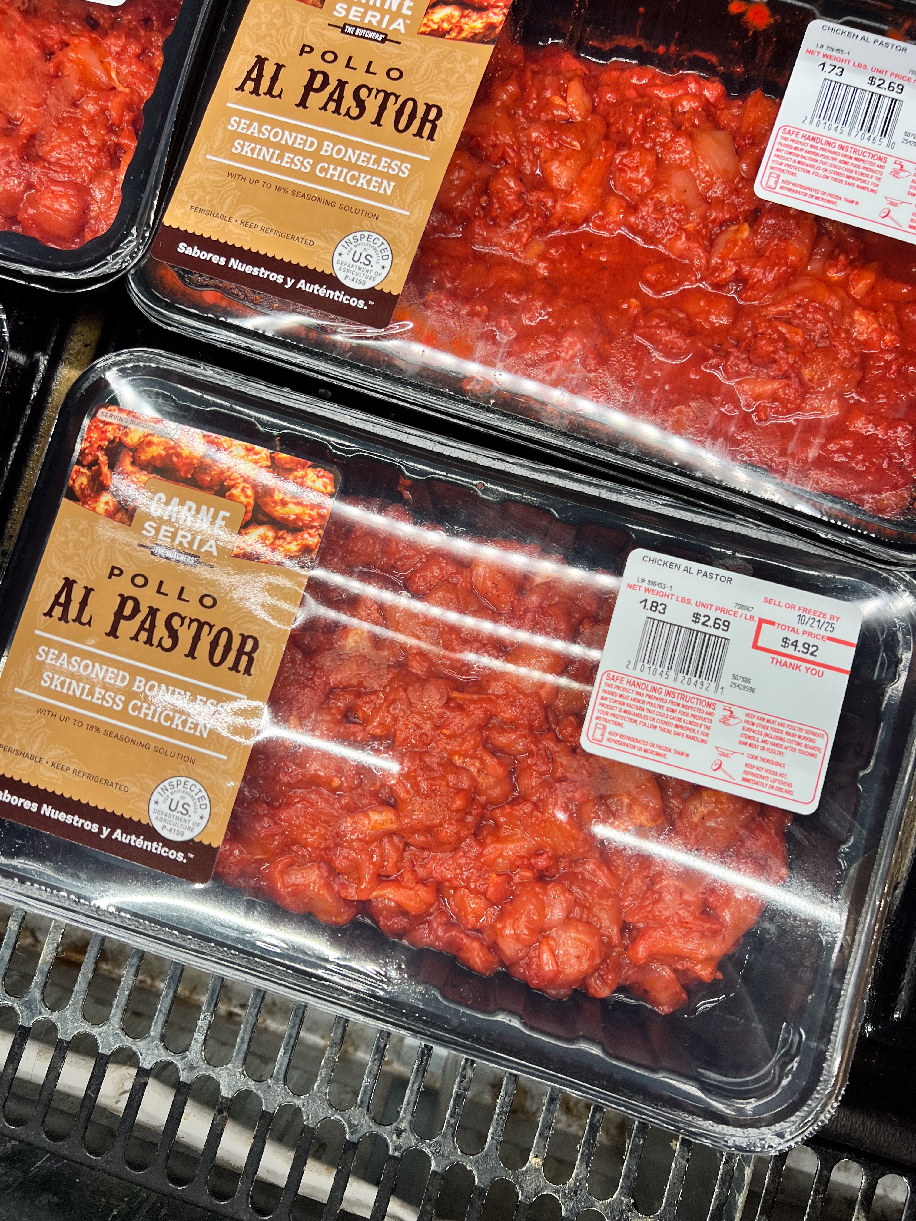 Packs of boneless, seasoned Pollo Al Pastor on display in a store. Each package has a price label and branding visible