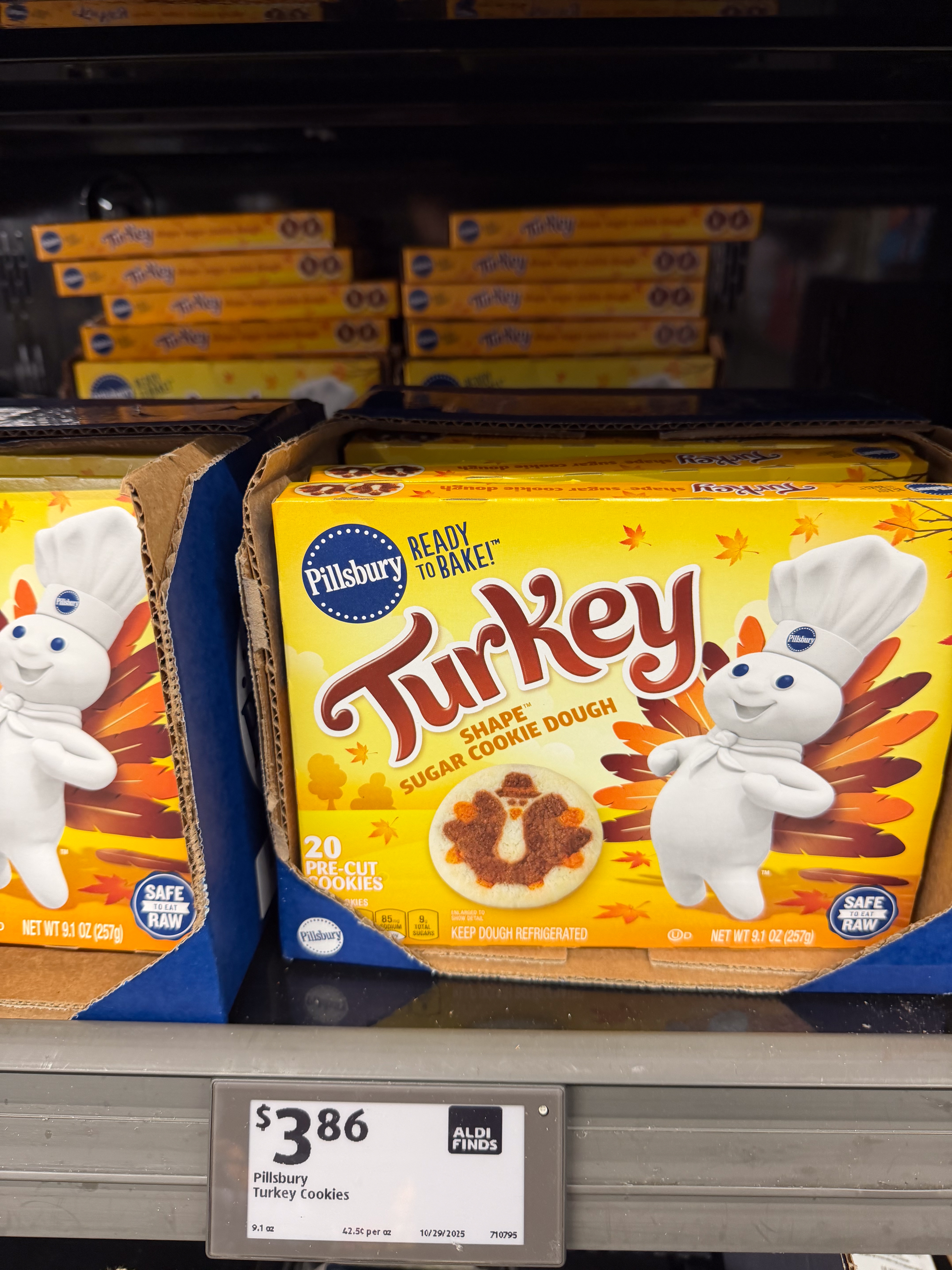 Pillsbury turkey-shaped sugar cookie dough packages on a store shelf, priced at $3.86