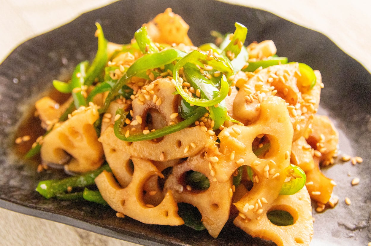 れんこんとピーマンのきんぴら。ごまが振りかけられ、風味が豊かに仕上がっている様子。皿に盛られている。