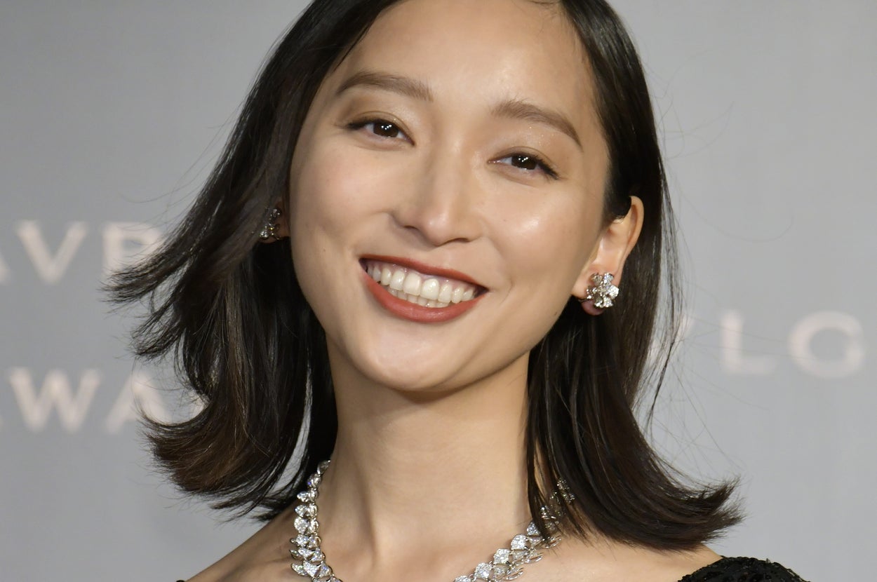 誰かはわかりませんが、この女性は宝石のネックレスとイヤリングを身に着けた豪華な黒い服を着ています。