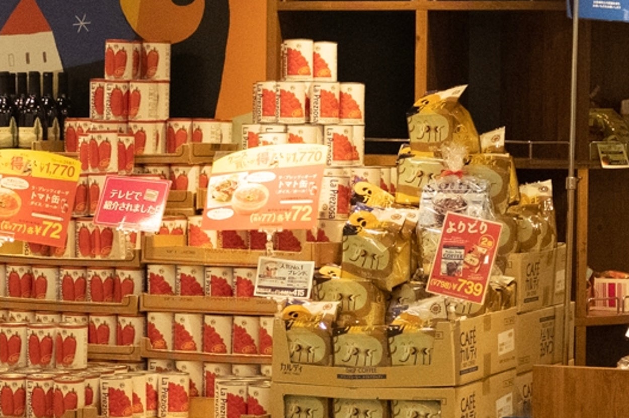 スーパーマーケットの店頭に多種多様な食品が並ぶ様子。商品には特売の看板があり、にぎやかな雰囲気が感じられる。