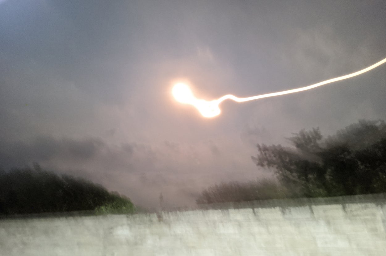 曇り空の下、光の筋が夜空に広がる幻想的な風景。