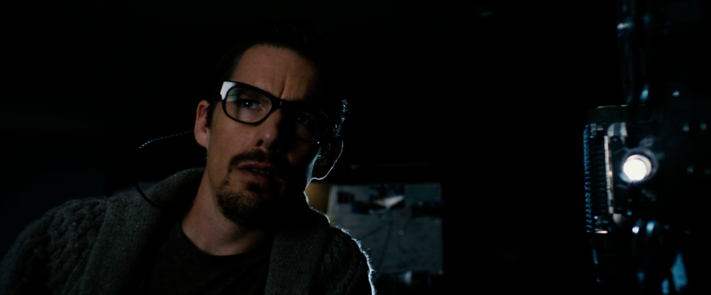 A idiosyncratic   with glasses looks intently astatine  a movie  projector successful  a dimly lit setting, evoking a suspenseful atmosphere