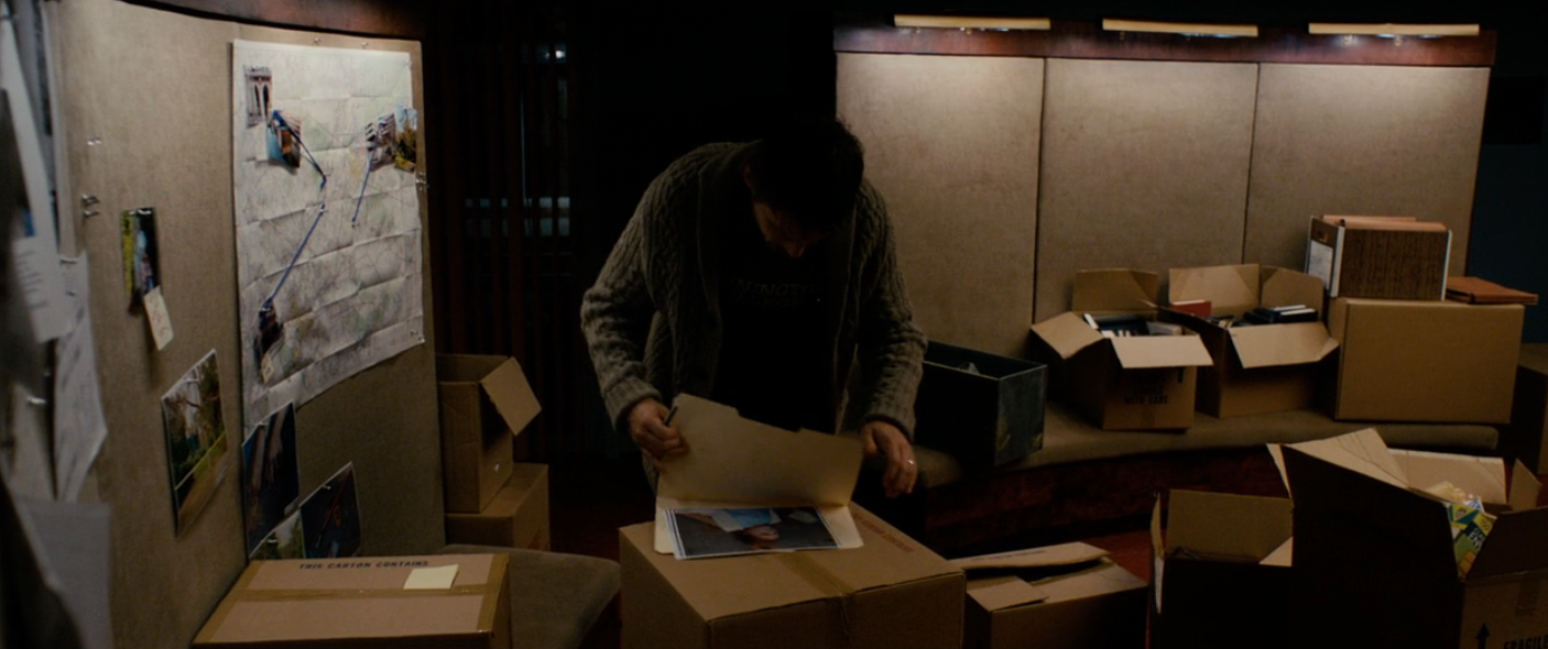 Person sorting photos and files among unfastened  boxes successful  a dimly lit country   with a partition  show  and bulletin board