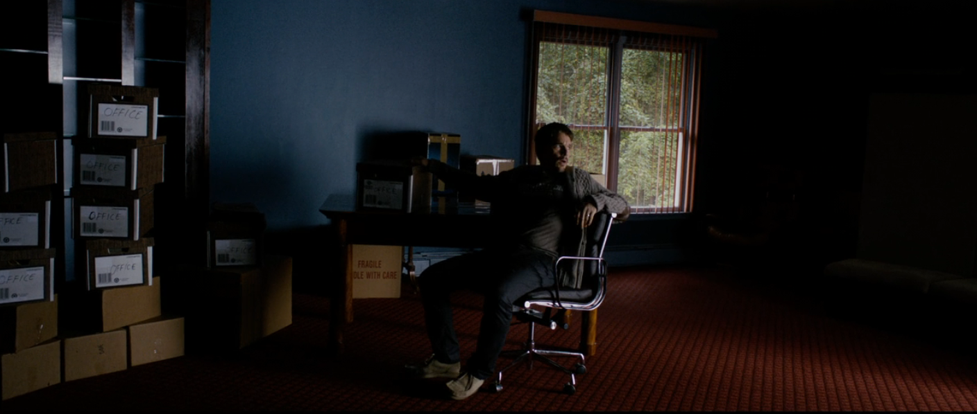 Person sitting successful  a dimly lit country   with cardboard boxes stacked around, adjacent   a model   showing greenery outside