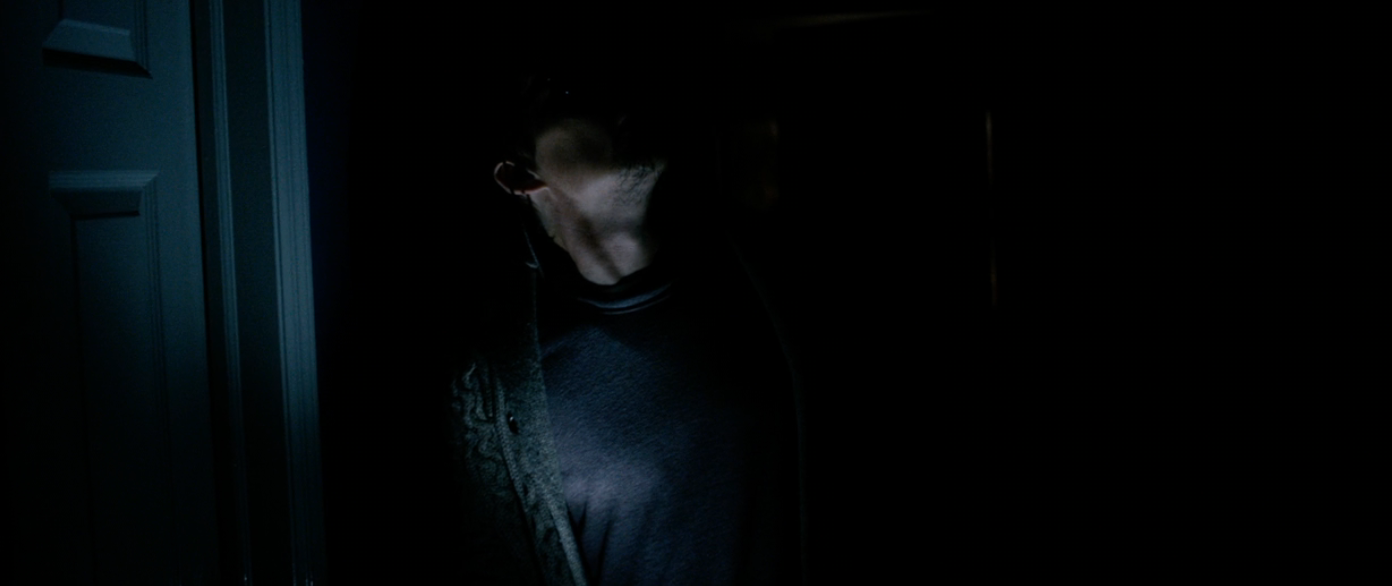 Person successful  a dimly lit room, partially obscured by shadows, with a doorway disposable   connected  the left