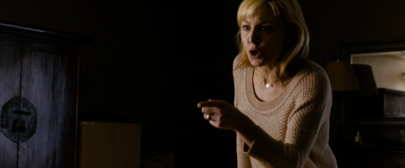 A pistillate   with blonde hair, wearing a knit sweater, gestures emphatically indoors, apt  during a melodramatic  scene