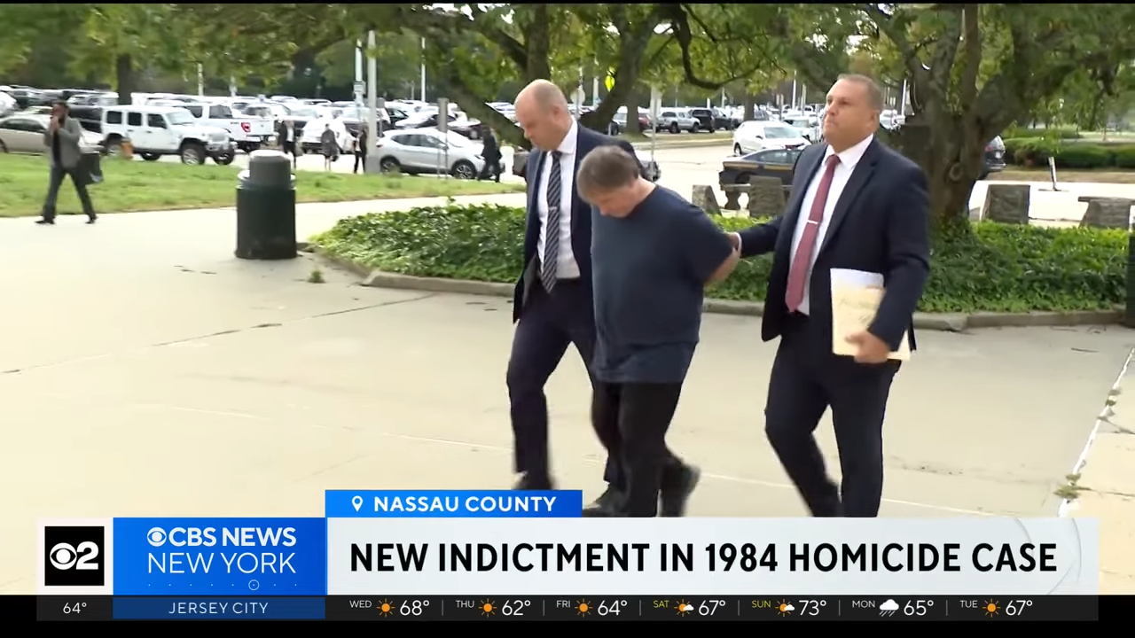 A antheral is escorted by 2 officers outdoors, related to a 1984 homicide case. Text beneath is simply a quality chyron from CBS News New York