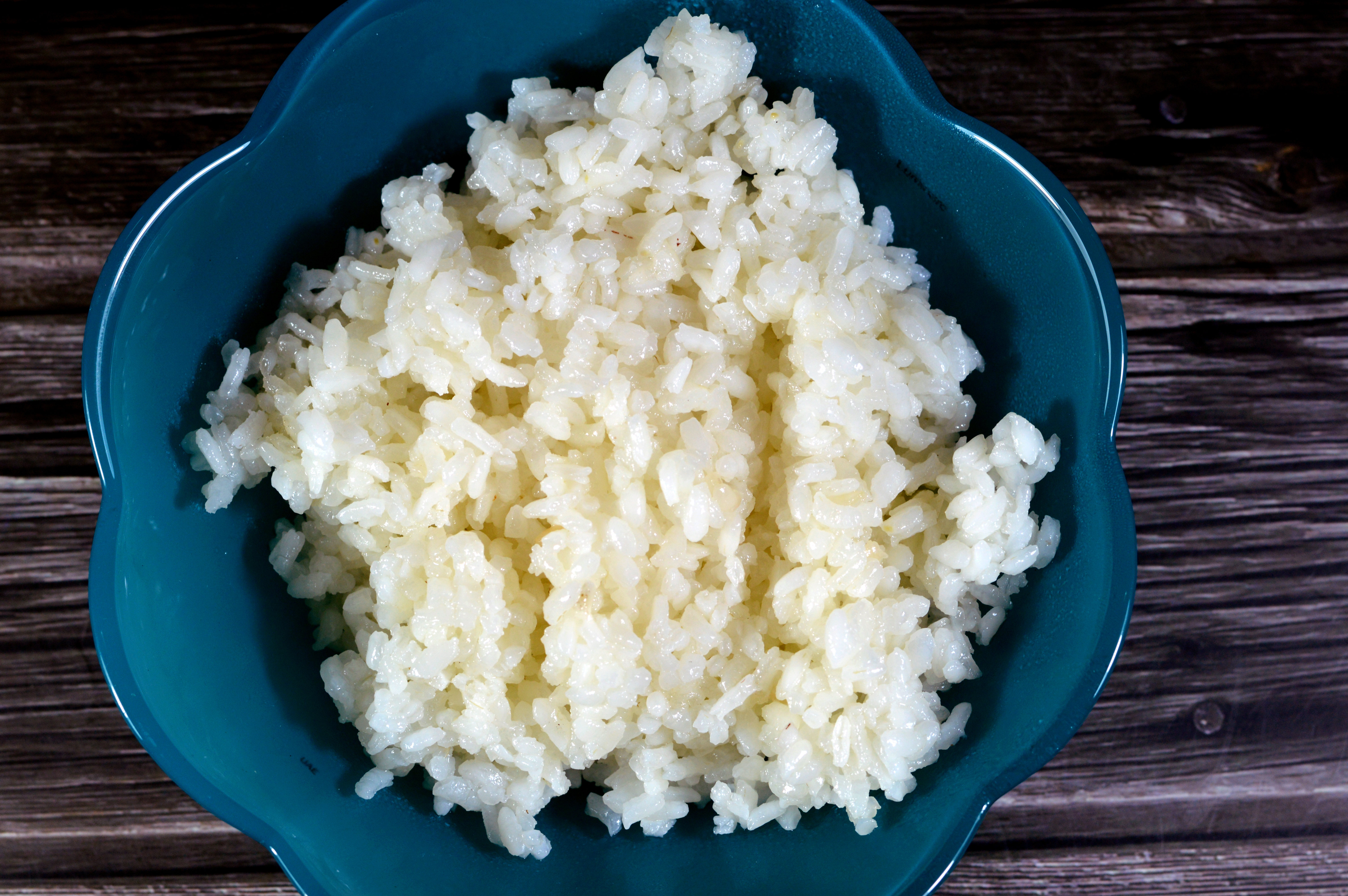 A bowl of cooked rice placed on a wooden table