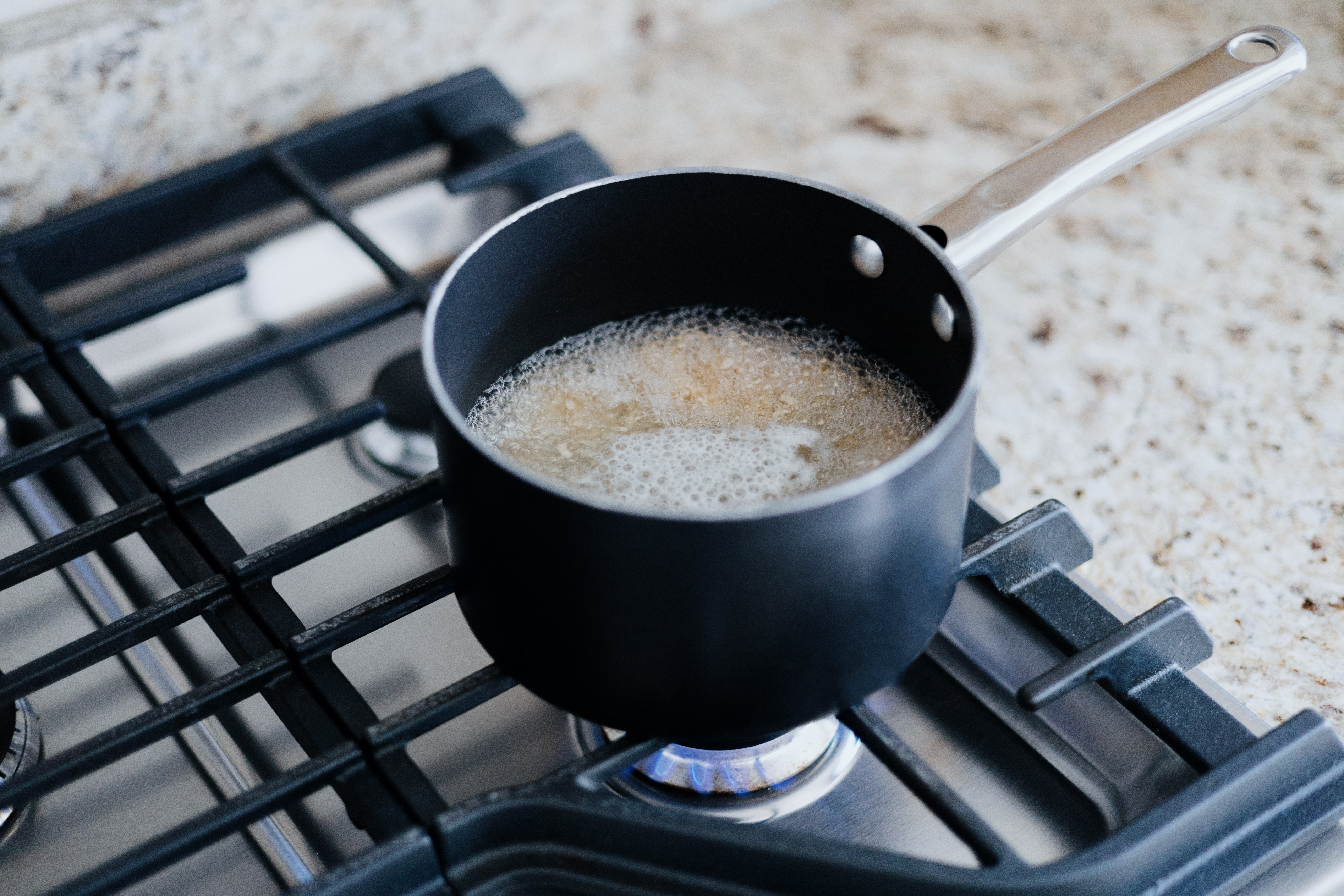 Small pot boiling on a stove, bubbles visible