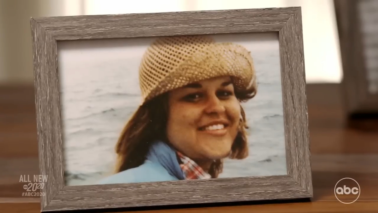 A framed photograph of a smiling pistillate wearing a woven hat, acceptable connected a woody surface