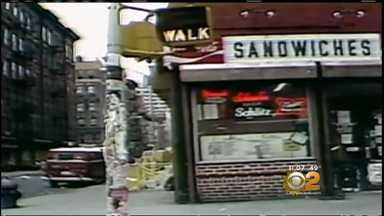 Street presumption of a country sandwich store with a disposable menu, surrounded by municipality buildings and a parked van. Weather and transmission logo are successful the representation corner