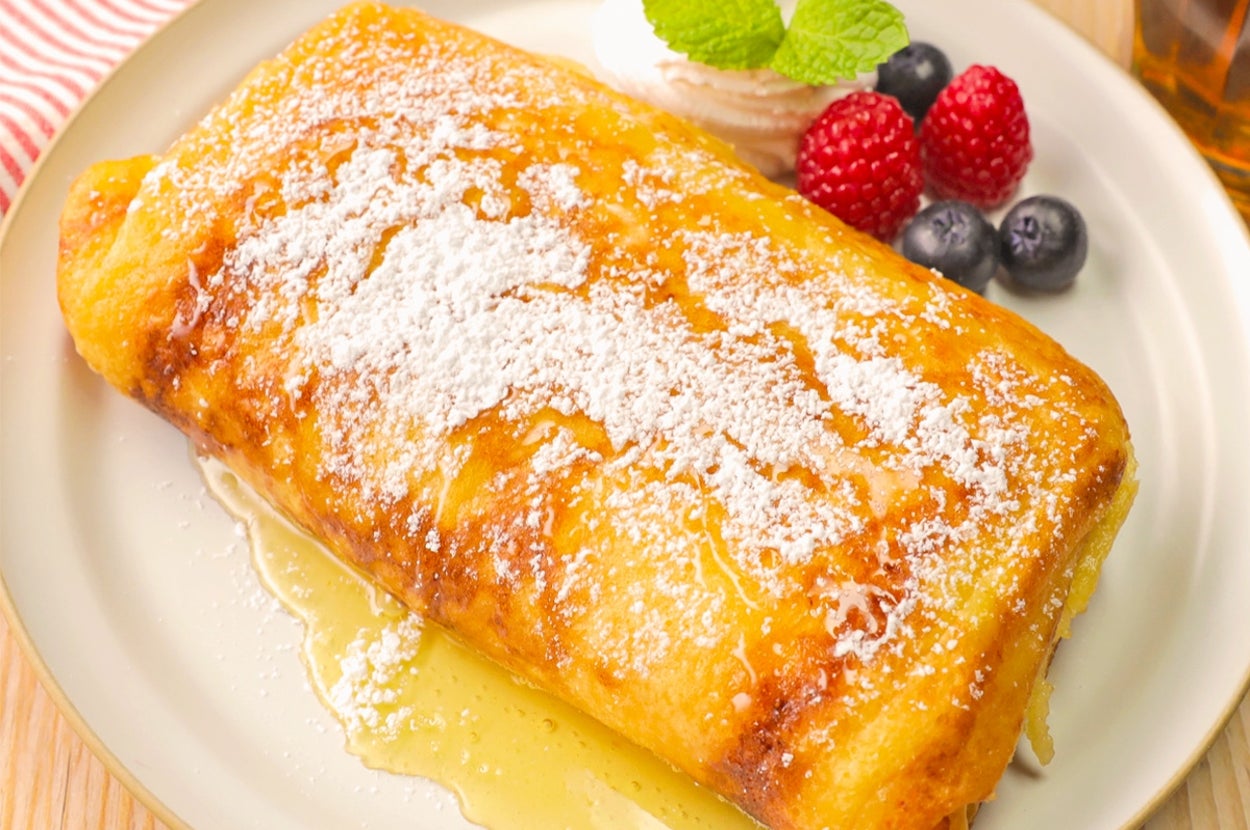 皿に盛られたパンケーキに粉砂糖がかかり、ホイップクリームやベリーが添えられている。