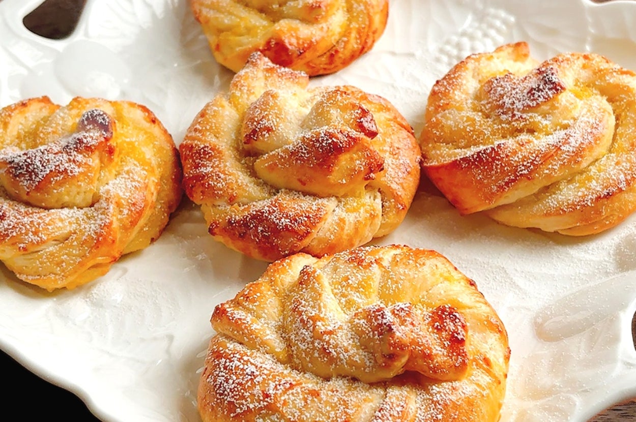 皿に盛られた5つのデニッシュペストリー。上には軽く粉砂糖がふりかけられている。