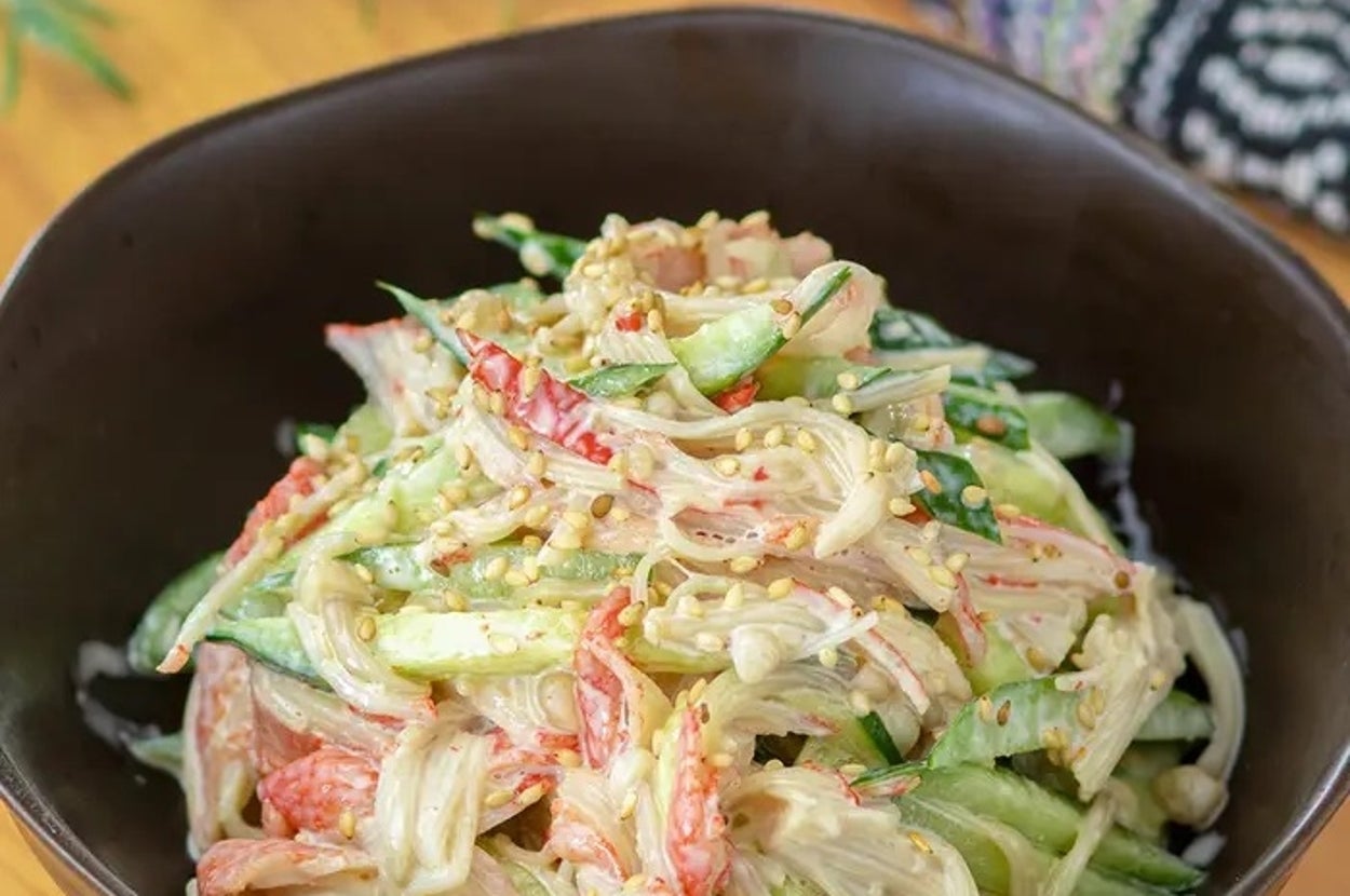 クリーミーなドレッシングで和えたキュウリとカニカマのサラダが黒いボウルに盛られている。