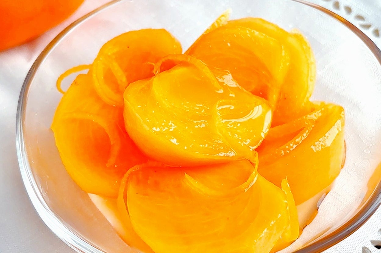 透明なボウルに盛られた新鮮な柿スライス。テーブルクロスの上に置かれ、美しく盛り付けられている。