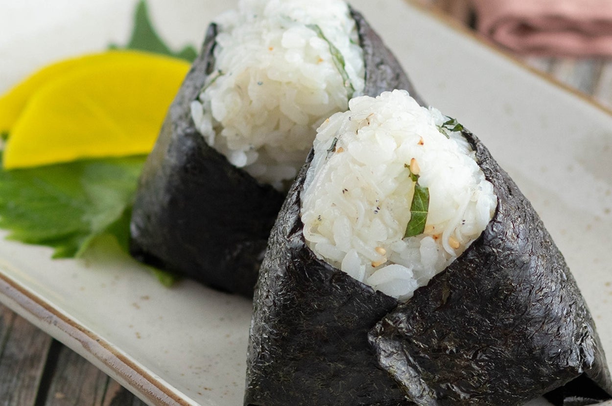 お皿に盛られた海苔で包んだ2つのおにぎりと、付け合わせのたくあん。