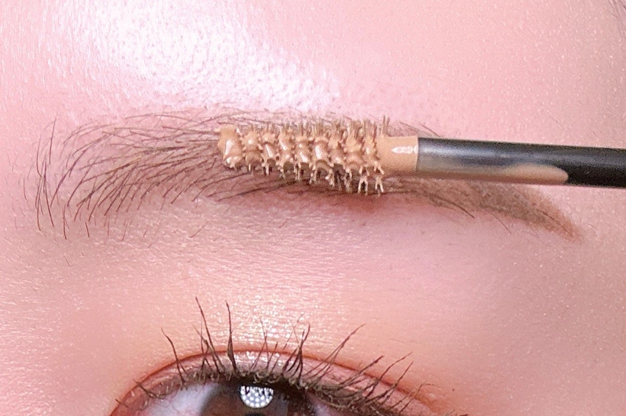 眉にブラシで眉マスカラを塗っている様子。目元にフォーカスした美容シーン。