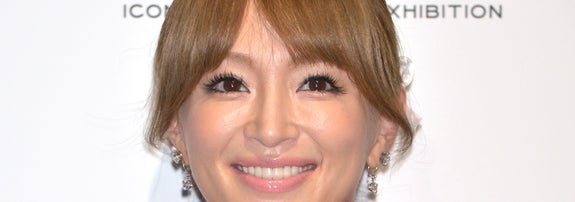 女性が赤いデザインドレスを着て笑顔を見せている。バックグラウンドに「MARC JACOBS」の文字。