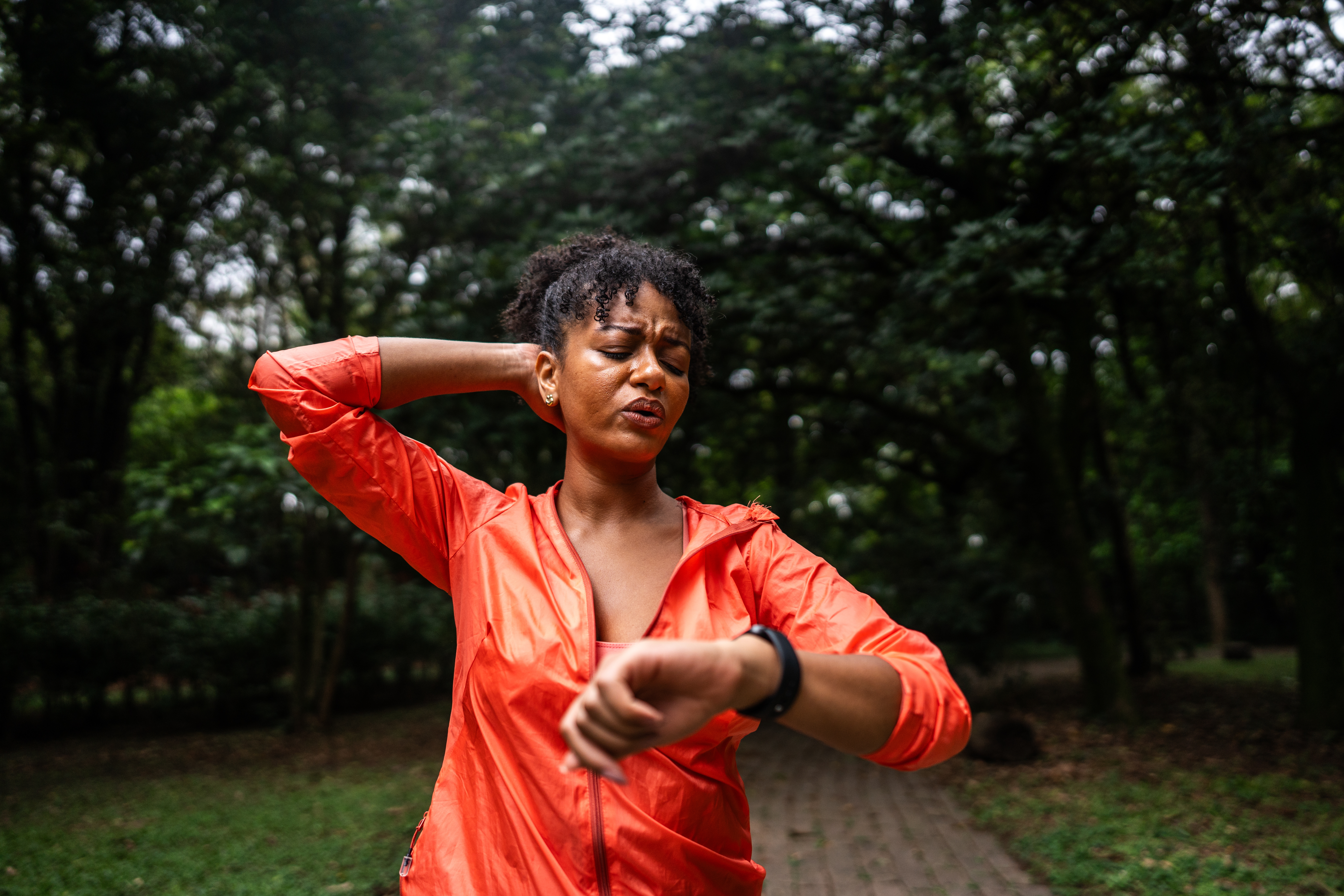 Person successful  activewear checks smartwatch successful  a park, wiping sweat from face, suggesting they&#x27;ve conscionable  finished exercising