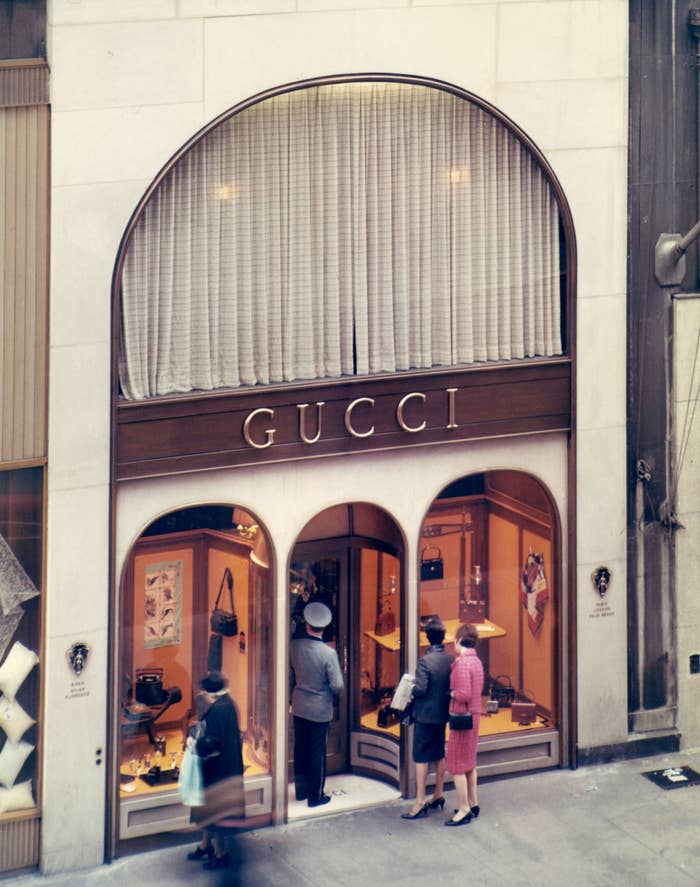 People window-shopping astatine  a vintage Gucci store   with elegant displays of handbags and accessories