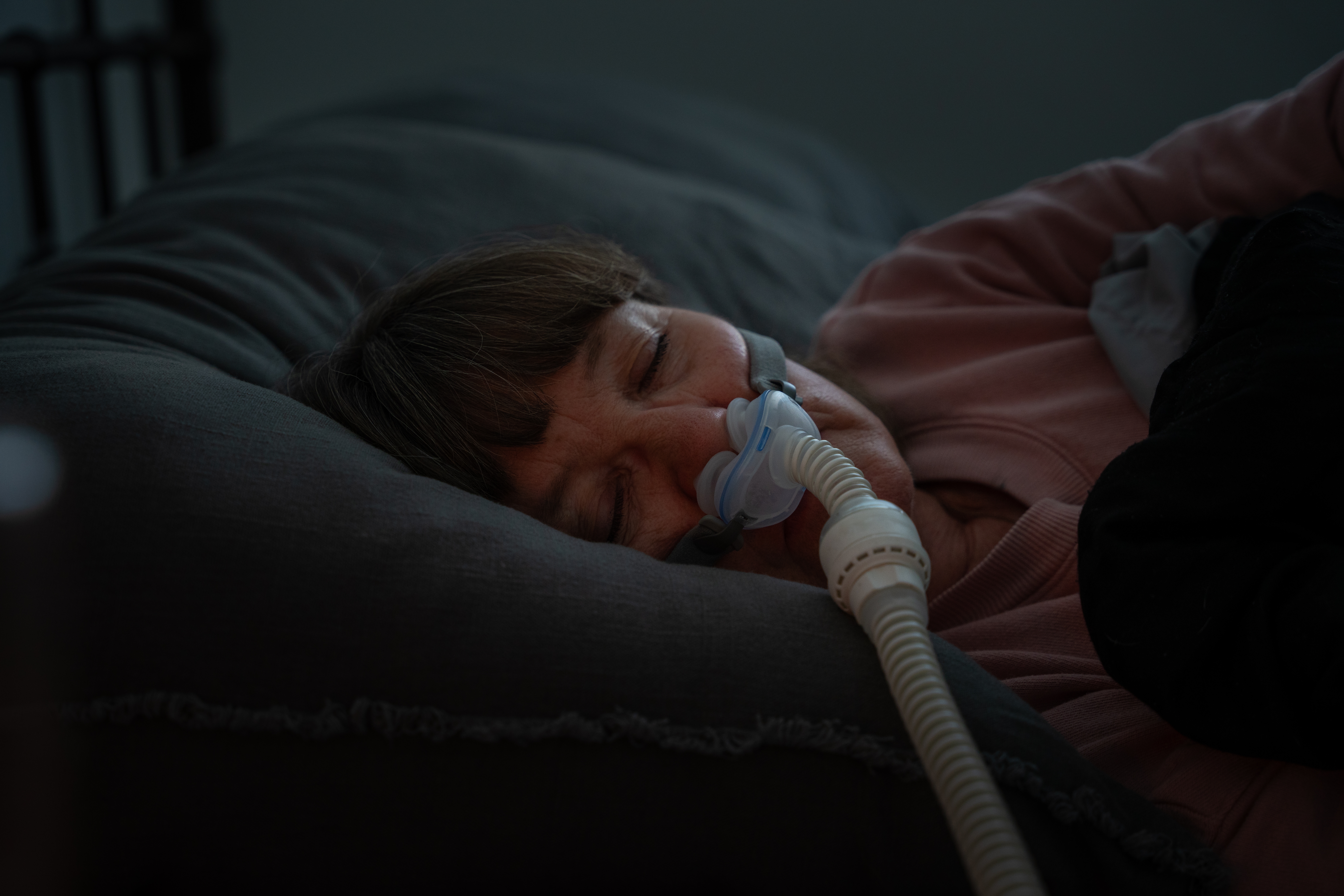Person sleeping with a CPAP mask, lying connected  a pillow