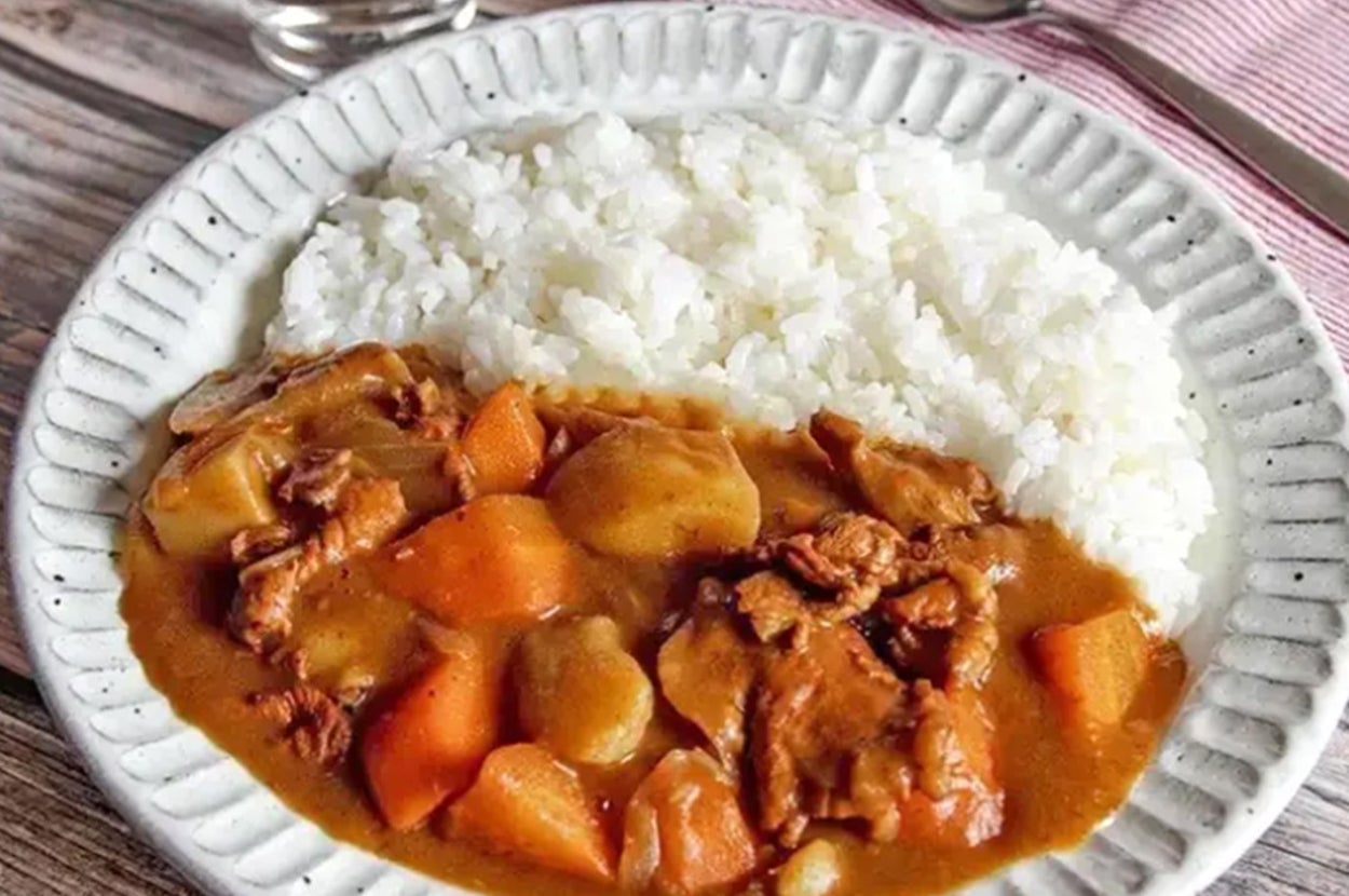 カレーライスの食事がプレートに盛られ、テーブルにスプーンとナプキンが置かれている。