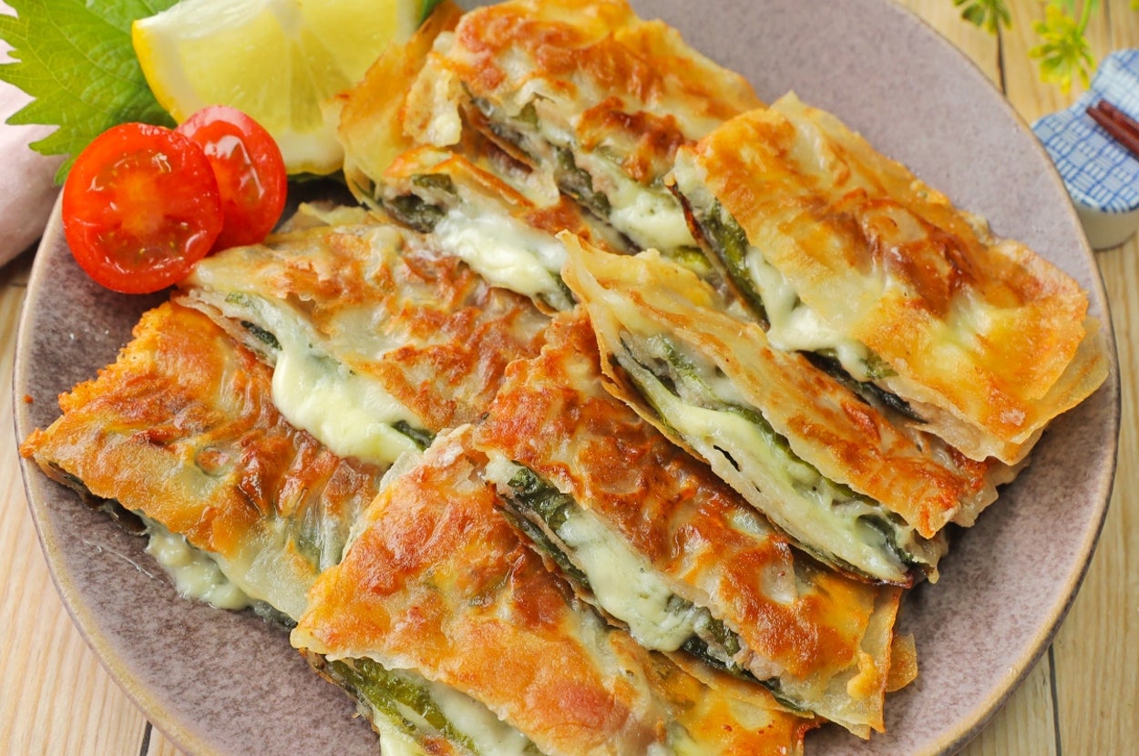 お皿に盛られた韓国風チーズチヂミ。トマトとレモンが添えられている。