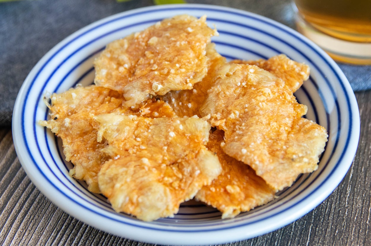 お皿に盛られたおつまみクラッカーとビールのグラスがテーブルに置かれている。広告用のシーン。