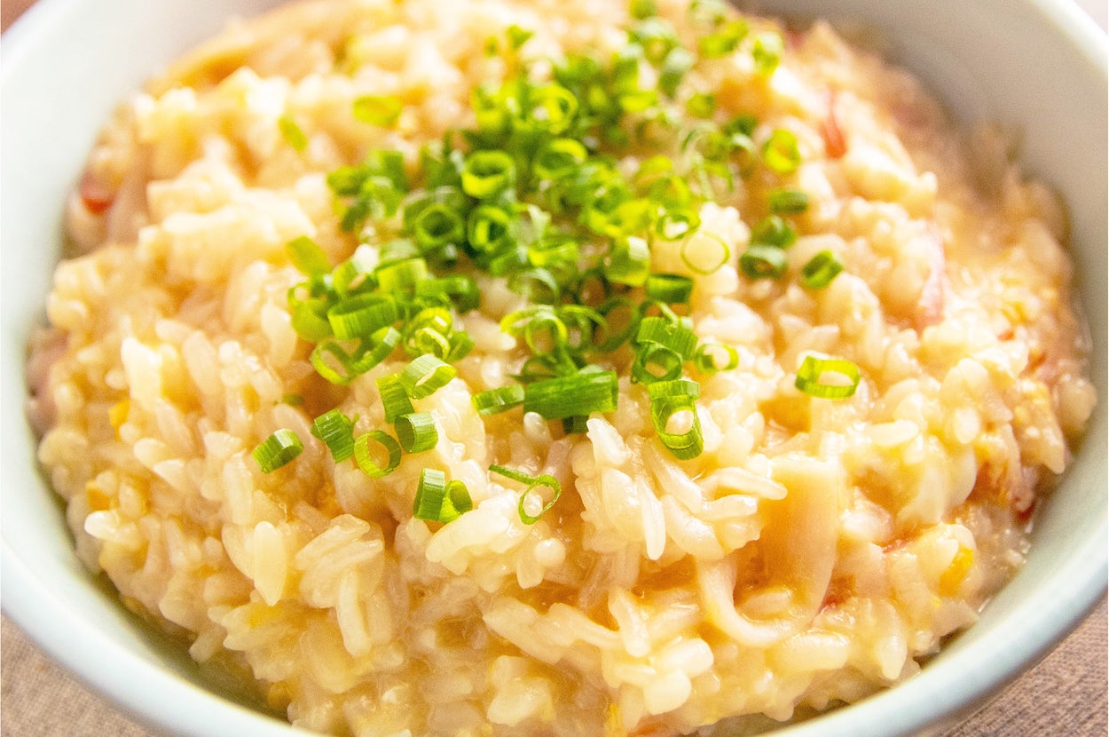 お粥の上に刻んだネギが乗った料理が白いボウルに盛られている。