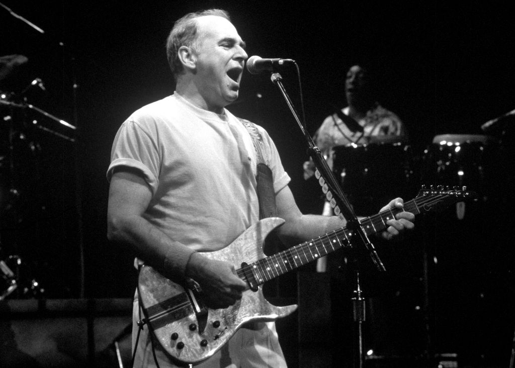 Musician passionately singing and playing guitar connected stage, dressed casually