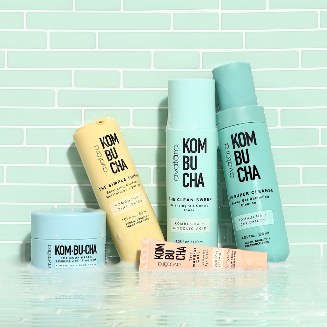 Skincare products displayed against a tiled background, featuring various bottles and tubes labeled as kombucha-infused for face and body care