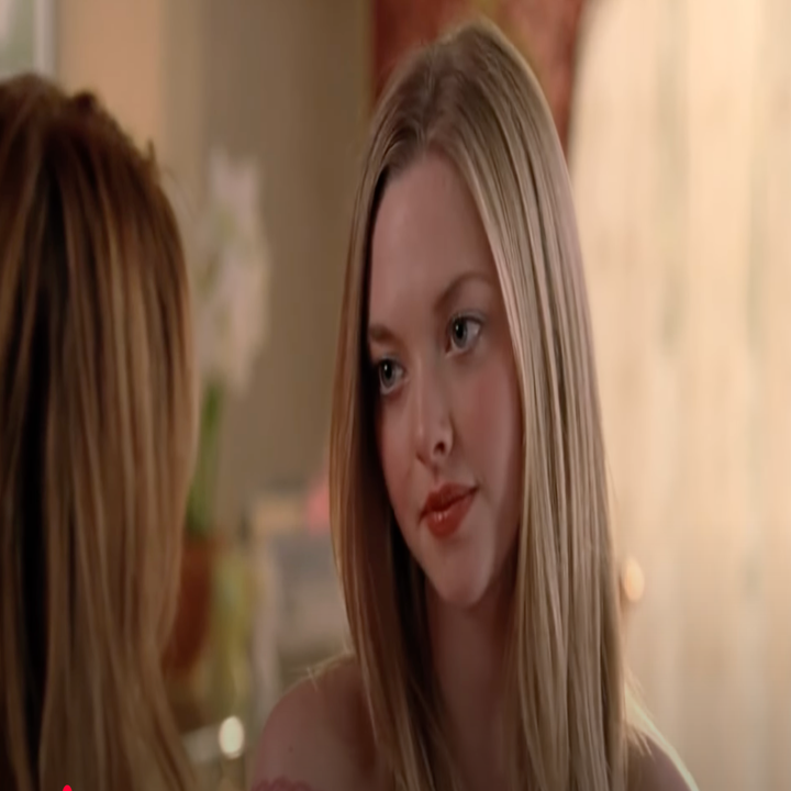 Two people having a conversation indoors, one with long blonde hair is looking intently at the other