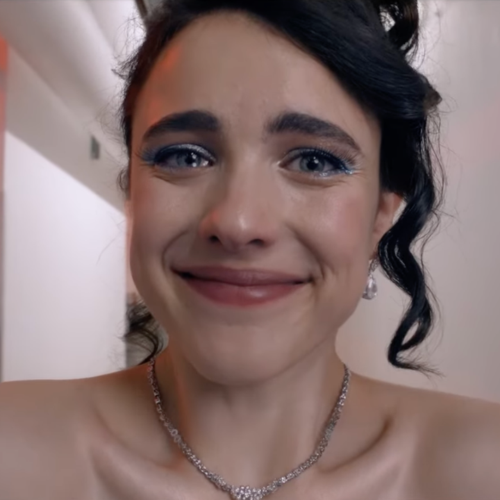 Woman with an emotional expression, wearing a necklace and off-shoulder dress, standing in a corridor