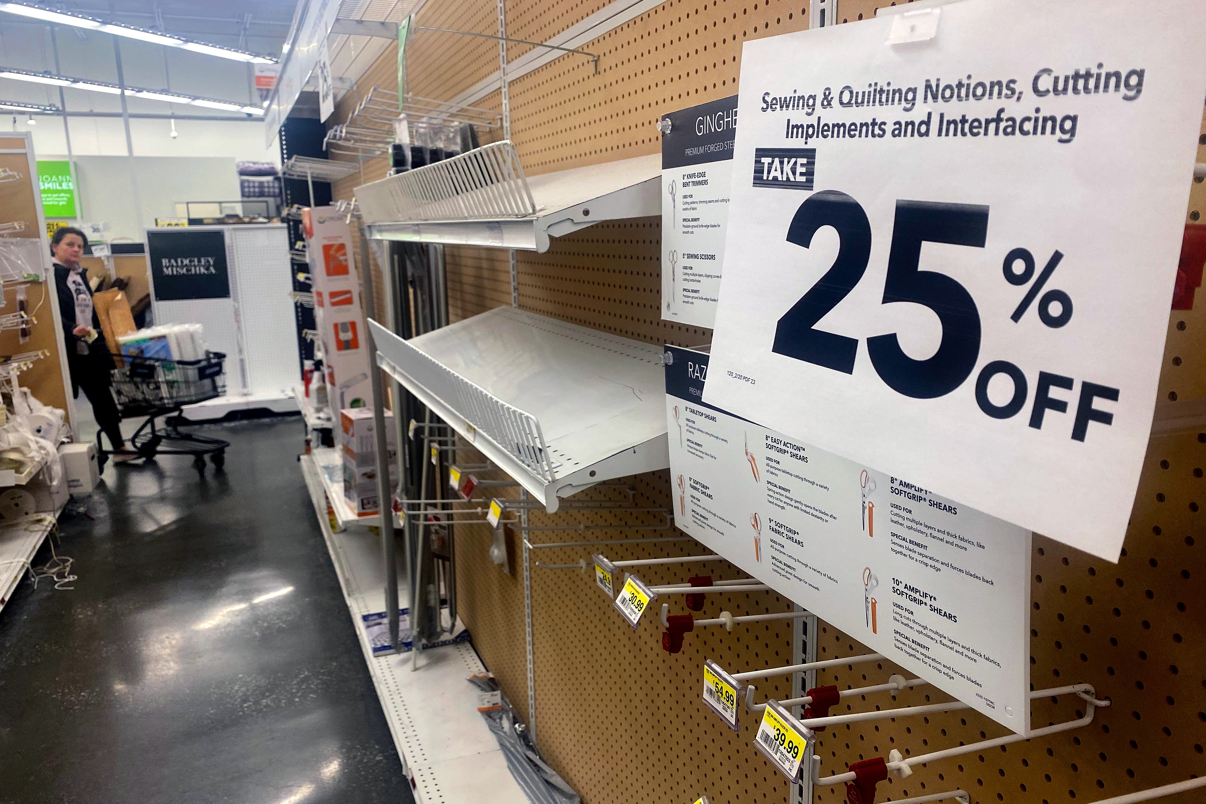 Sale sign at a store offering 25% off on sewing and quilting notions, cutting implements, and interfacing. Shelves appear partially empty