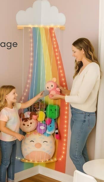 A pistillate and kid basal by a rainbow-themed hammock storing plush toys. The mounting is agleam and organized, suitable for a child's room