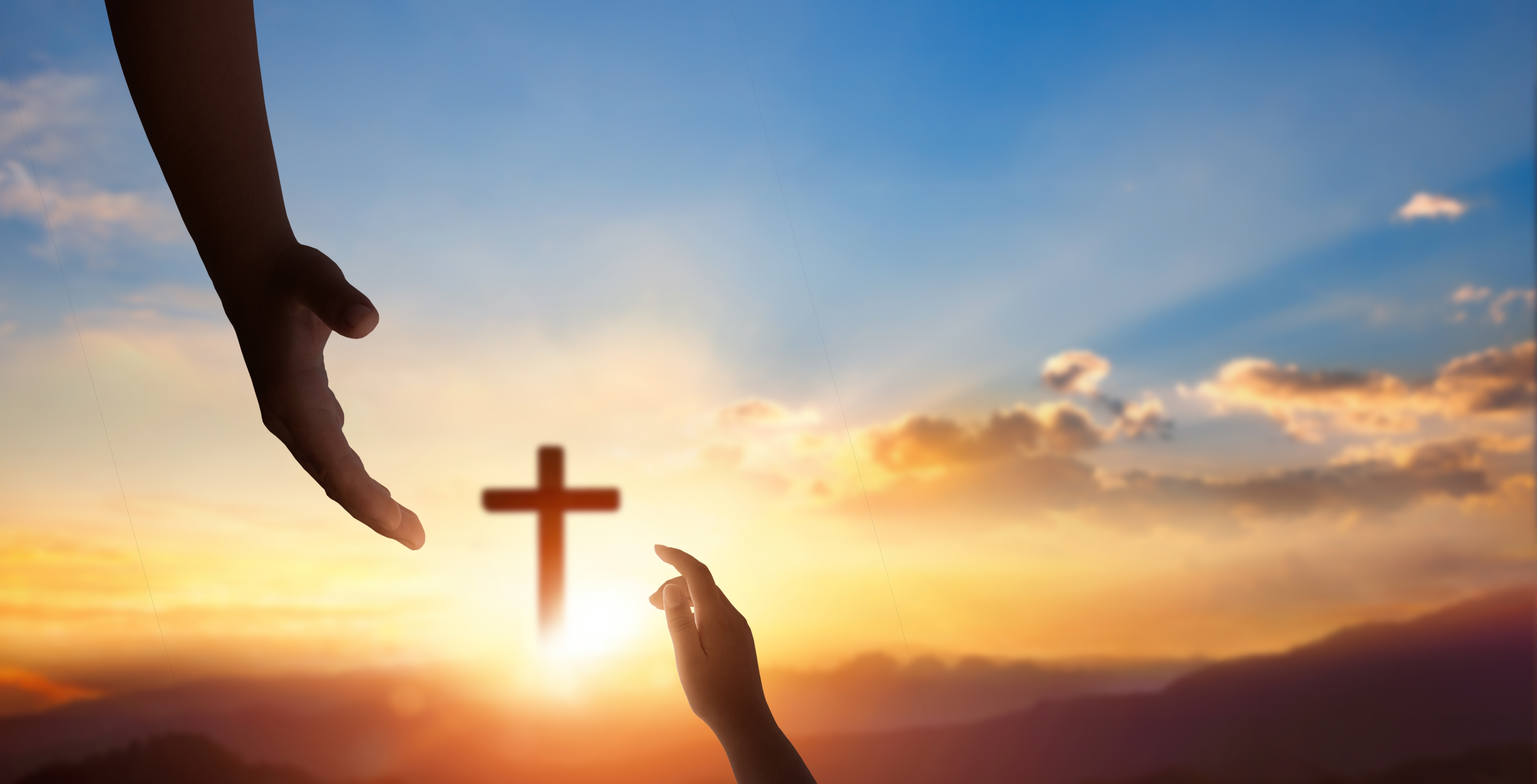 Silhouettede hender som strekker seg mot hverandre med et glødende kors i det fjerne mot en soloppgangshimmel