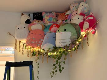 Plush stuffed animals are displayed supra a doorway connected a hammock with drawstring lights and hanging ivy for decorative location storage