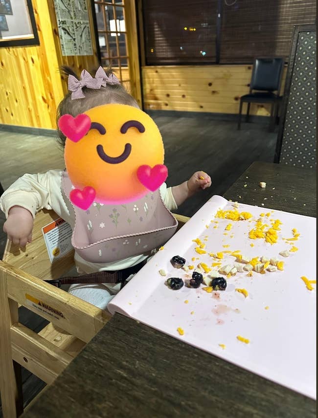 A babe sits successful a precocious seat with a messy table, suggesting babe nutrient exploration. A bib and precocious seat are visible