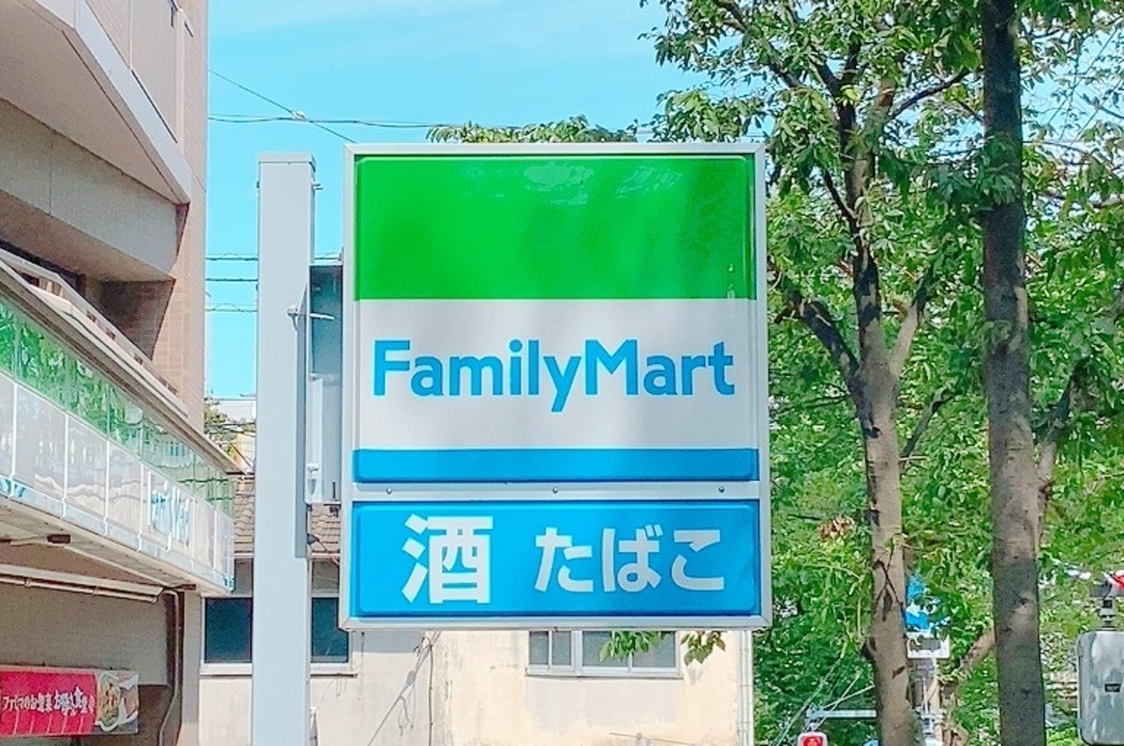 ファミリーマートの看板と「酒 たばこ」の表示。背景に建物と木々が見える。