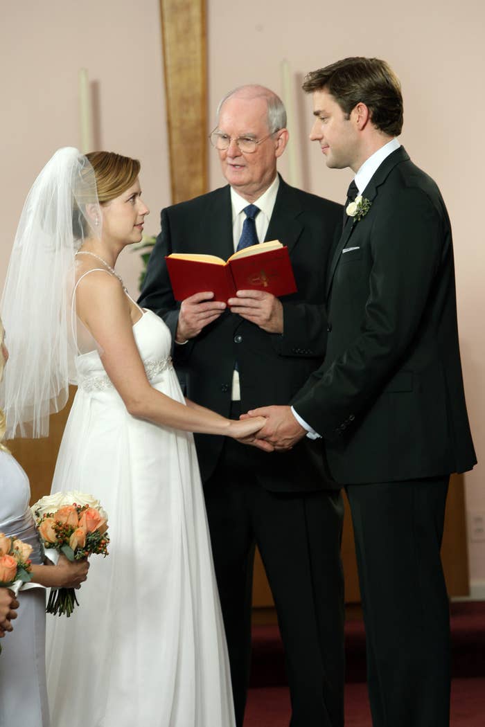 A mates  holds hands successful  a wedding ceremony, officiated by a minister. The bride wears a veil; the groom is successful  a suit