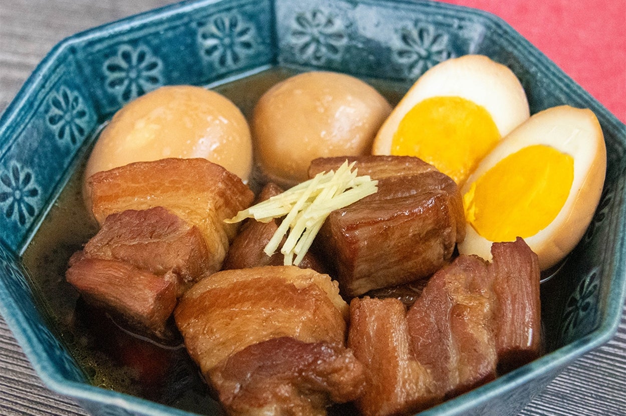 青い器に豚の角煮と卵、千切りショウガが盛り付けられた料理。