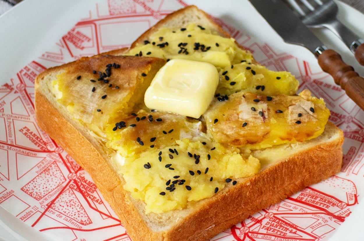 バターと黒ゴマがのったスイートポテトのトーストが皿に載っている。隣にフォークとナイフがある。