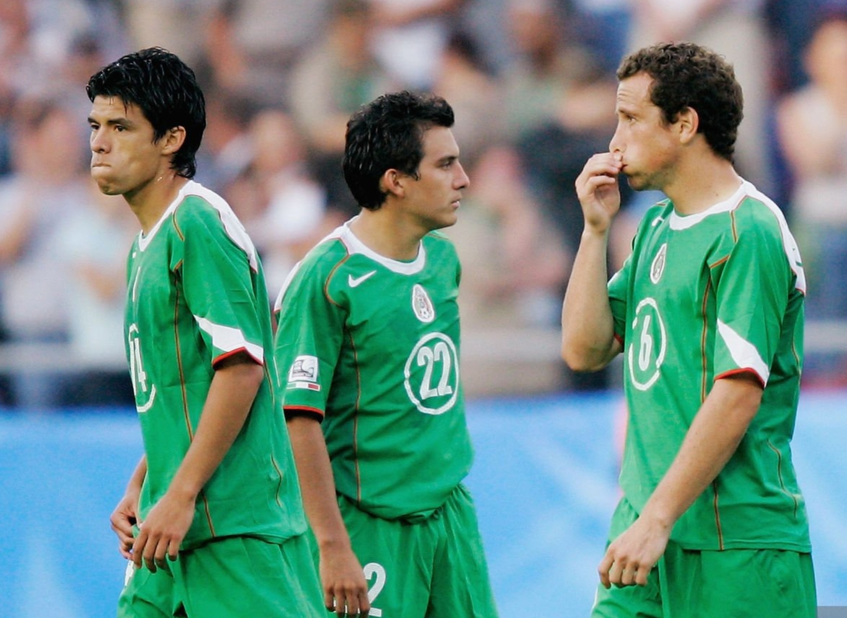 Five soccer players in matching uniforms stand on a field, engaging in conversation and adjusting their positions