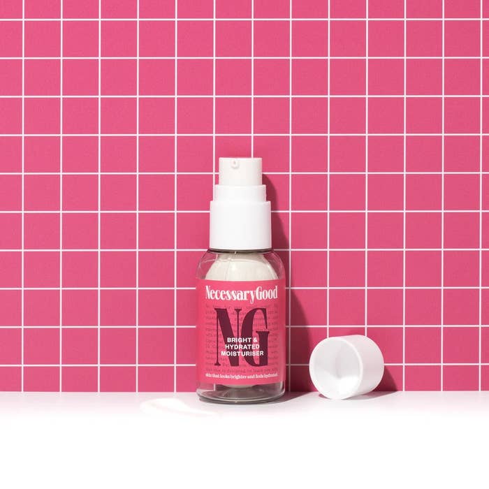 Moisturizer vessel  labeled &quot;NecessaryGood&quot; stands connected  a grid-patterned background, with a headdress  beside it