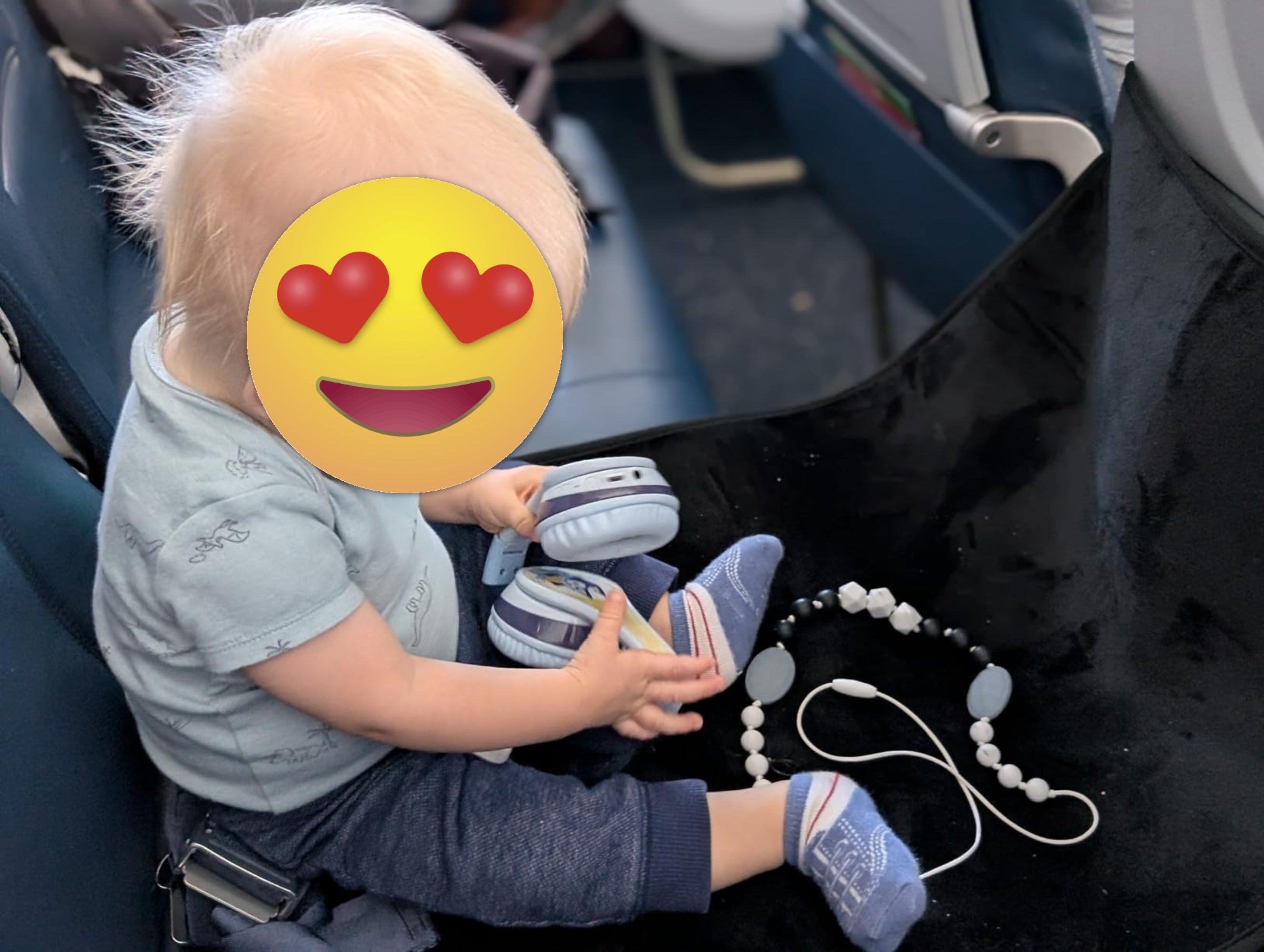 A babe  connected  an airplane spot   plays with headphones and a pacifier clip portion    wearing a airy  garment  and pants